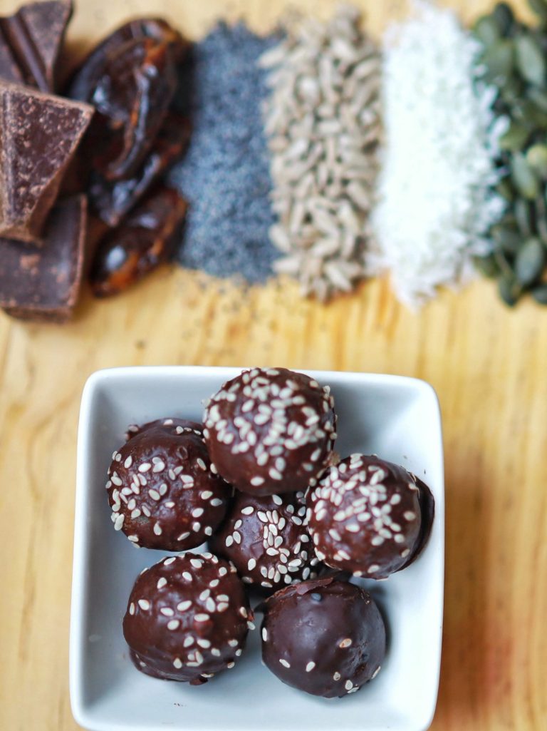 chocolate coated energy balls with seeds, dates, and coconut flakes